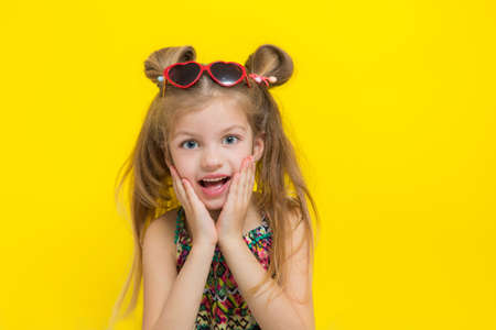 Cute little girl in sun glasses on the yellow background in the studio.の写真素材