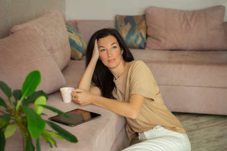 Attractive young woman enjoying coffee and relaxing at home.の写真素材