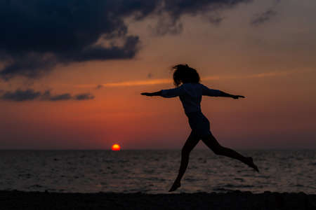 Happy young woman having fun with open hands at the sunset on sea.の写真素材