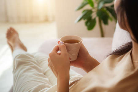Attractive young woman enjoying coffee and relaxing at home.の写真素材