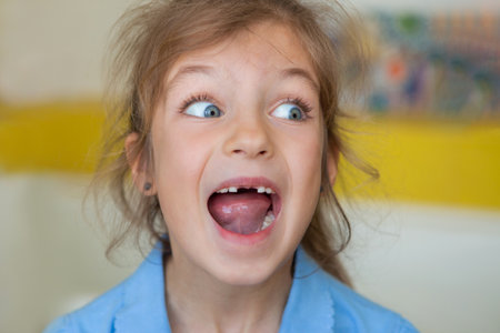 Beautiful little girl lost the first milk tooth. Happy child dropped the first milk tooth.