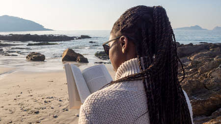 Portrait of young woman reading a book on a sunny day by the seaの写真素材