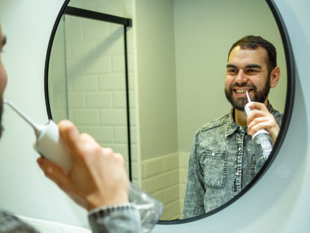 <p>Healthy Oral Hygiene: Young Man Using domestic dental water flosser in Bathroom Mirror</p>の写真素材