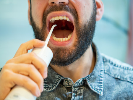 Healthy Oral Hygiene: Young Man Using domestic dental water flosser