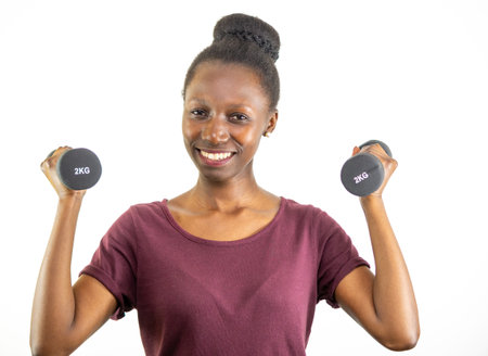 Young woman lifting two dumbbells isolated on white backgroundの写真素材