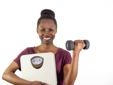 Young woman showing a weight scale while lifting a dumbbell isolated on white backgroundの写真素材