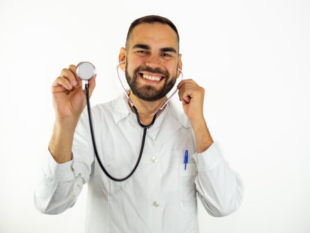 Young male doctor using his stethoscope at camera while smiling. Looking at camera isolated on white backgroundの写真素材