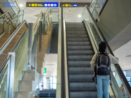 Woman with backpack on escalator in modern metro station or airportの写真素材