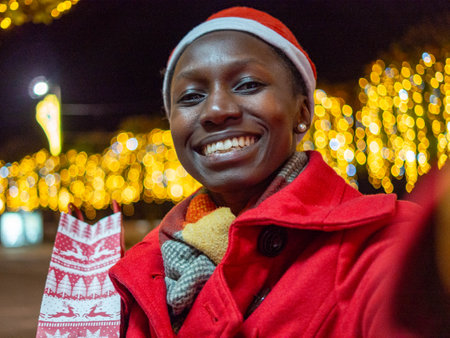 Unidentified woman in red coat and Santa Claus hat at Christmas market.の写真素材