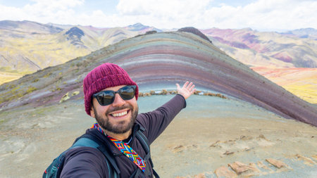 young bearded traveler taking a selfie on the peak of the Rainbow mountain in Peruの写真素材