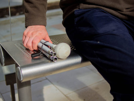 Blind man sits on bus stop bench with folded cane beside himの写真素材