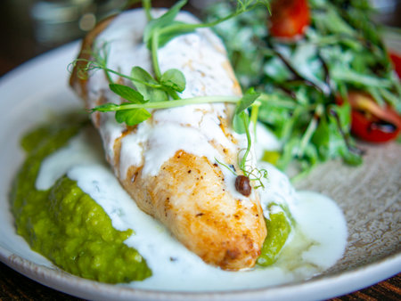 Grilled salmon fillet with green peas and sauce on a plateの写真素材