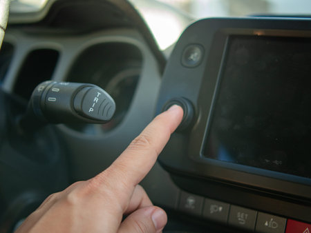 Close-up of a man's hand turning the button on a car dashboard