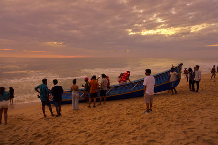 VARKALA, KERALA, INDIA - DECEMBER 31, 2021: Men pushing the boat to the sea to take tourists for a trip.のeditorial素材