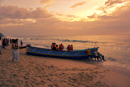 VARKALA, KERALA, INDIA - DECEMBER 31, 2021: Men pushing the boat to the sea to take tourists for a trip.のeditorial素材