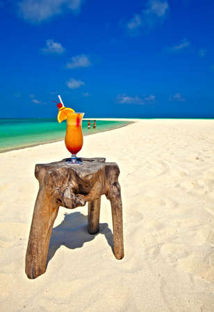 Bocal of cocktail is on original  beach table is made from trunk of treeの写真素材