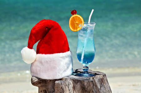 Bocal of tonic water is on original  beach table is made from trunk of tree with Santa hatの写真素材