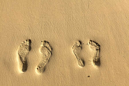 Two pairs footsteps on the coral sandy beach