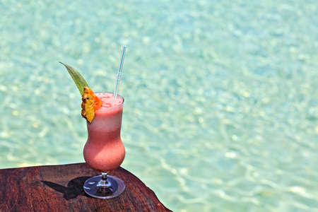 Glass of the soft drink is on a beach table (Maldives, The Indian Ocean)の写真素材