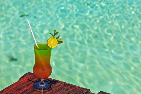 Glass of the soft drink is on a beach table (Maldives, The Indian Ocean)