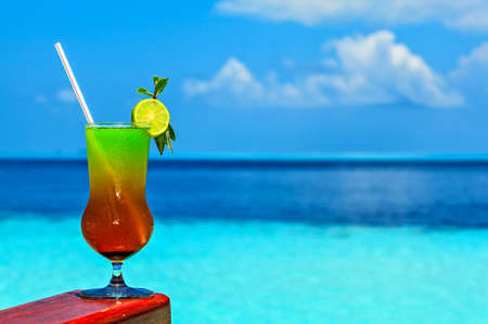 Glass of the soft drink is on a beach table (Maldives, The Indian Ocean)の写真素材