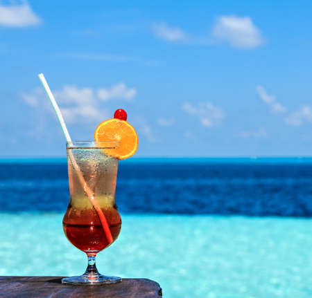 Glass of the soft drink is on a beach table (Maldives, The Indian Ocean)の写真素材