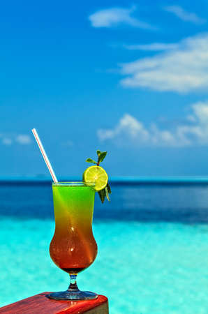 Glass of the soft drink is on a beach table (Maldives, The Indian Ocean)の写真素材