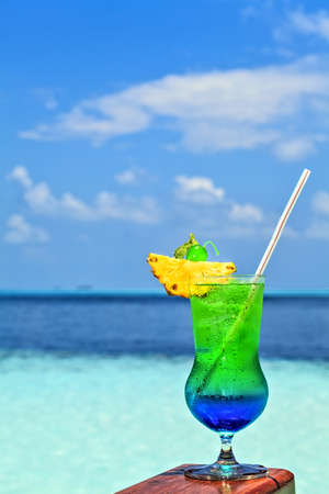 Glass of the soft drink is on a beach table (Maldives, The Indian Ocean)の写真素材