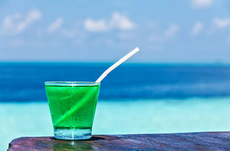 Glass of the soft drink is on a beach table (Maldives, The Indian Ocean)の写真素材