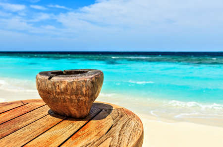 Ashtray made of coconut is on a beach tableの写真素材