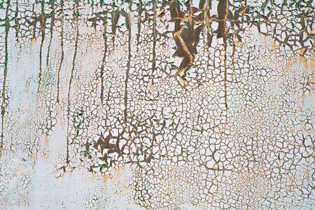 Painted metal with cracks in the paint, roughness. Cracking and flaking paint on rusty iron background. Close-up of a metal or steel plate, covered with old paint. Detailed photo texture.の写真素材