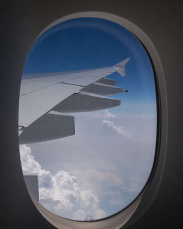 Beautiful view of the blue sky and white puffy clouds outside, as seen from the window of an...