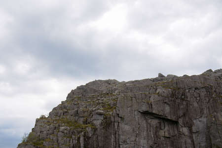 Beautiful details of the jagged rock face against the bright cloudy sky in the background at Preikestolen in Norway.の写真素材