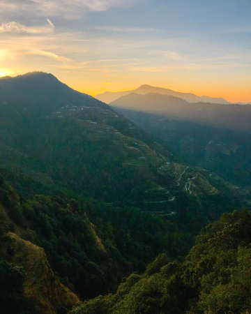 Beautiful sunrise behind the hills. Rays of sunshine shining on the villages on the slopes of the mountains. Dramatic sky.の写真素材