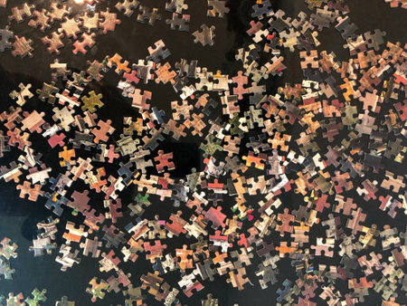 High angle view of many pieces of puzzle scattered on the wooden floor.