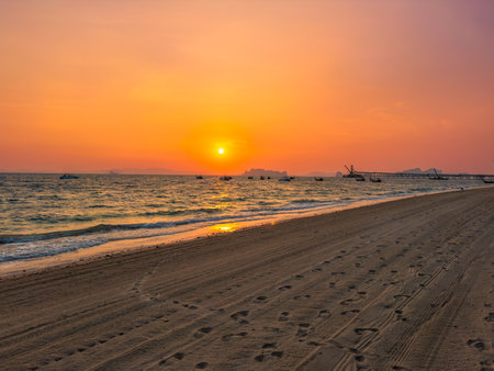 Fiery red tropical sunset on the Klong Muang beach in the province of Krabi in Thailand. Long-tailed boats in the sea.の写真素材