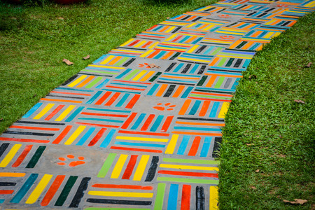 The colorful ceramic walking path on green grass field. Fun and lively walkway.の写真素材
