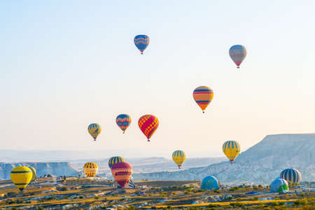 Colorful hot air balloons flying over stunning nature landscape of Cappadocia, Turkey with morning sky and white mistのeditorial素材
