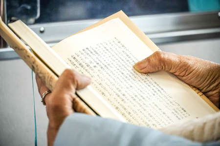 Closed-up view of asian Japanese elder adult hands holding and reading a Japanese book. Japan reading a hardcover paper book backgroundのeditorial素材