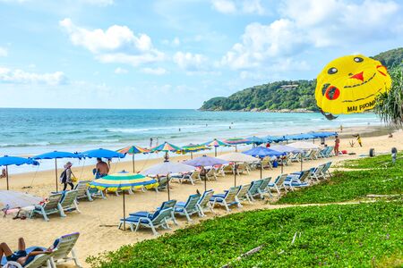 People going to beach under bright sunny sky with benches and colorful beach umbrella by the sea, Phuket, Thailand. Summer beach activity backgroundの写真素材