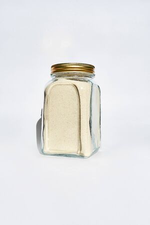 A jar of semolina with metall lid stands on a white background. Eco-friendly use of packaging.の写真素材
