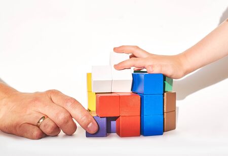 Close-up father and son hands hold blocks of different colors. Family game at home. Board game....