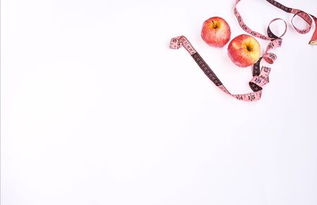 Weight loss concept. Red apples and pink measuring tape on white background.の写真素材