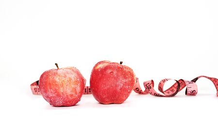 Red apples and pink measuring tape on white background.の写真素材