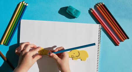 Child draw by colour pencils. Baby circle the yellow ruler by pencil. View from above, hands....