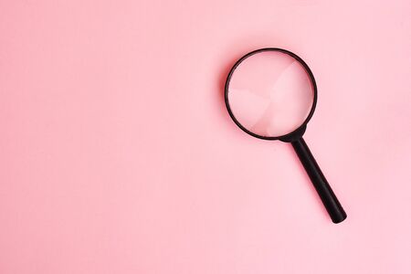 Close up Single Magnifying Glass with Black Handle, Leaning on pink background. Top view. Copy spaceの写真素材