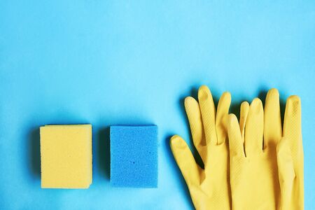 Yellow gloves and sponge on a blue background. Space for textの写真素材