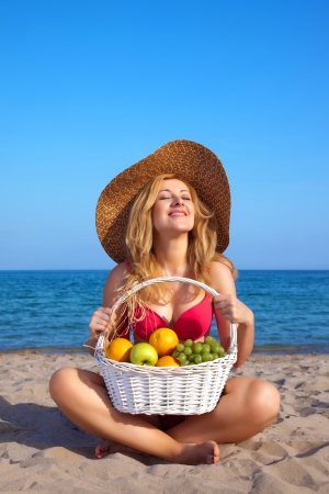 Attractive woman with basket of fruits on a seacoastの写真素材