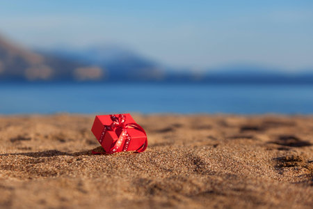 Red gift box on a beachの写真素材