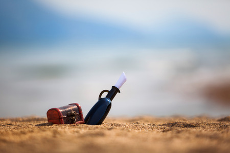 Black bottle and chest on a beachの写真素材